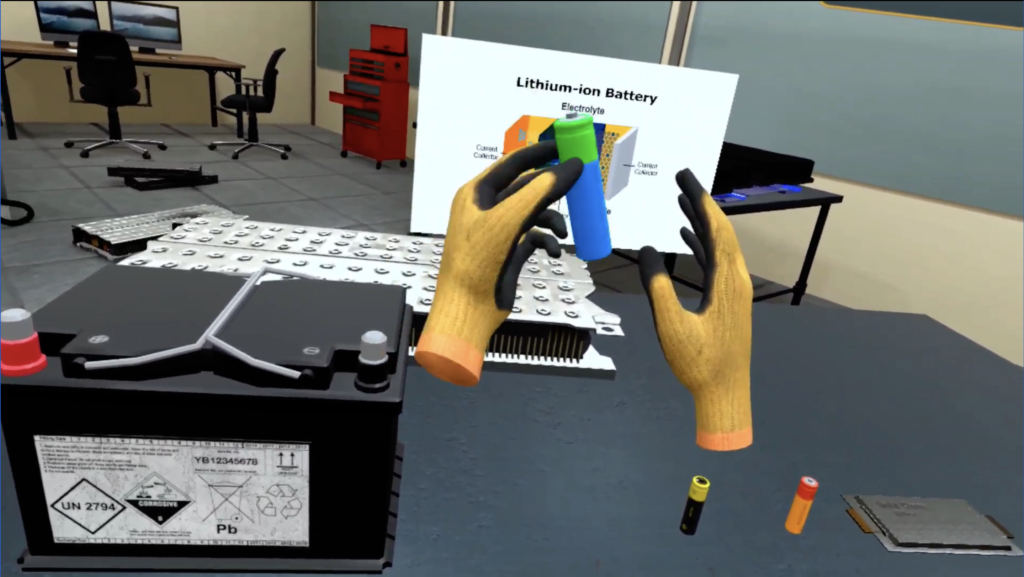 ImmerseLearn VR simulation: first-person view of hands holding Lithium-ion Battery diagram over workbench with various battery types (lead-acid, EV module, cells).